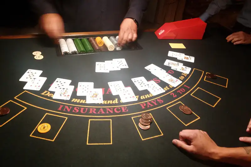 A dealer’s hands at a blackjack table with playing cards and a chip tray