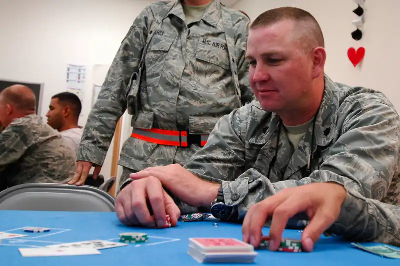 Men seated at a casino-night poker table, one of them stacking his chips